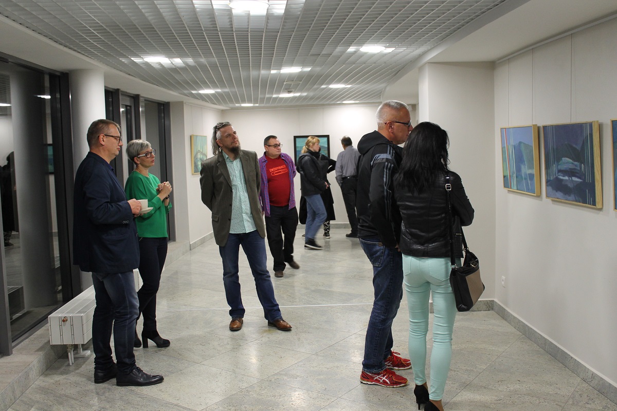 Uczestnicy wystawy oglądają prace rozwieszone na ścianach galerii
