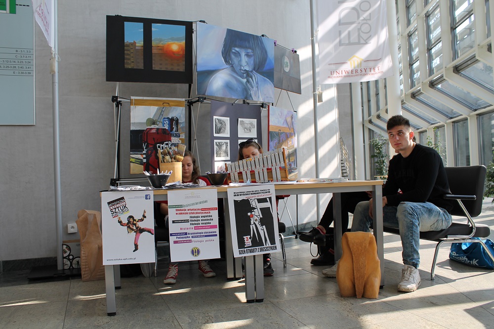 Studenci zakładu sztuki artystycznej siedzą na stoisku promującym ich kierunek studiów