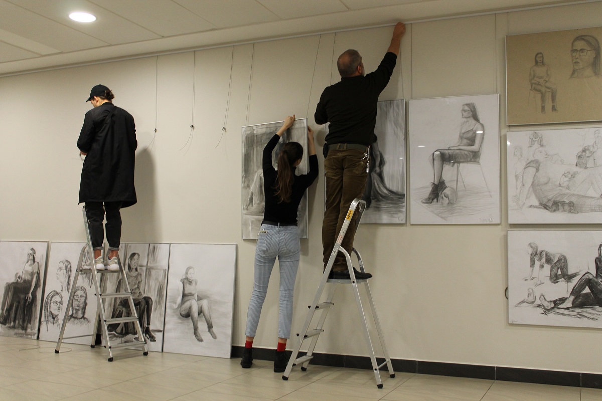 Studenci montują prace na ścianie galerii